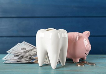 A giant tooth and piggy bank, symbolizing the cost of cosmetic dentistry in Columbia