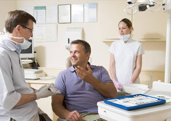 Man in dental chair talking to dentist