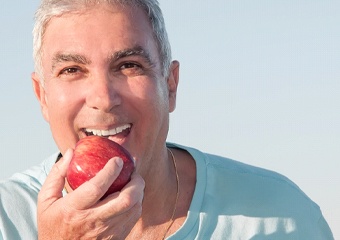 older man smiling holding apple