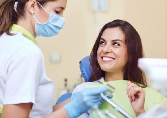 Smiling woman in dental chair speaking with dental professional