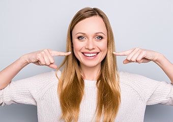 Young woman pointing to her healthy smile