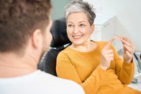 A woman holding a dental bridge at her dentist’s office