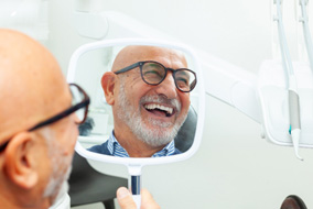 : A man smiling at his new dental bridge