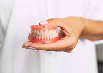 dentist holding set of full dentures