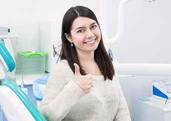 Woman in dental chair giving thumbs up