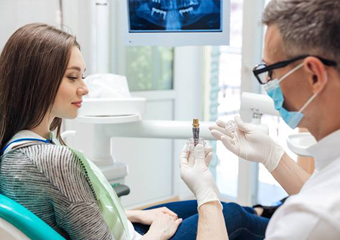 Dentist showing woman a dental implant model