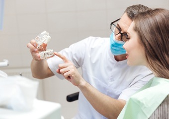 Dentist and patient looking at implant supported fixed bridge model