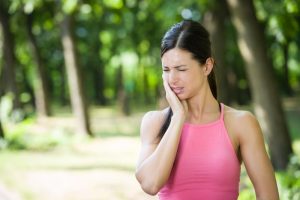 woman experiencing tooth pain while exercising outside 